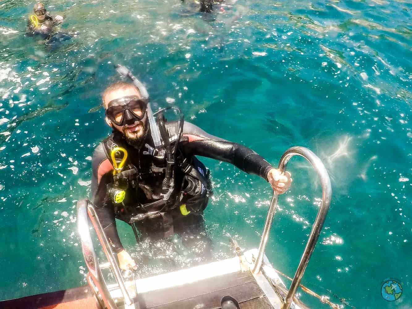 André nas escadas do barco com o equipamento. Curso de mergulho open water diver com a mar do Rio